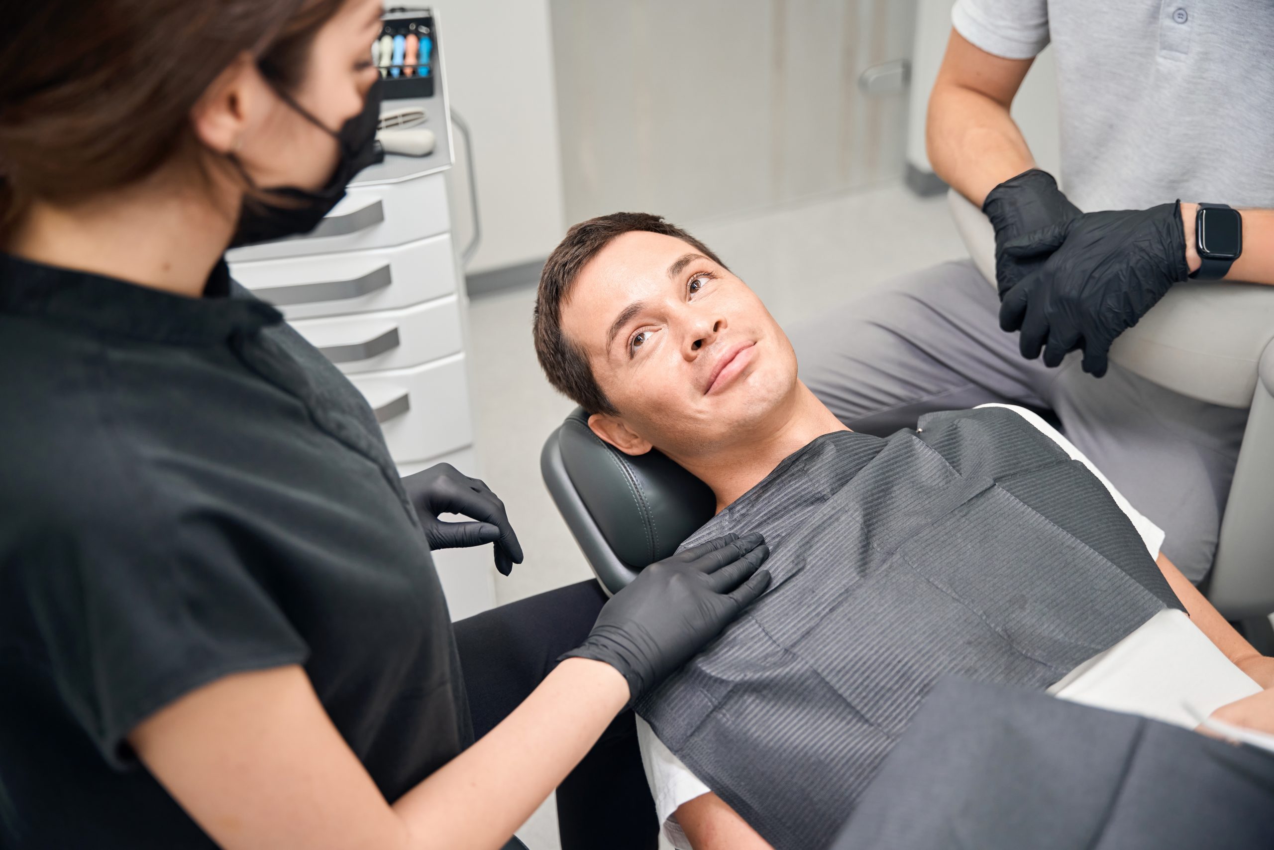 Nice brunette woman dentist calming down patient before teeth check-up