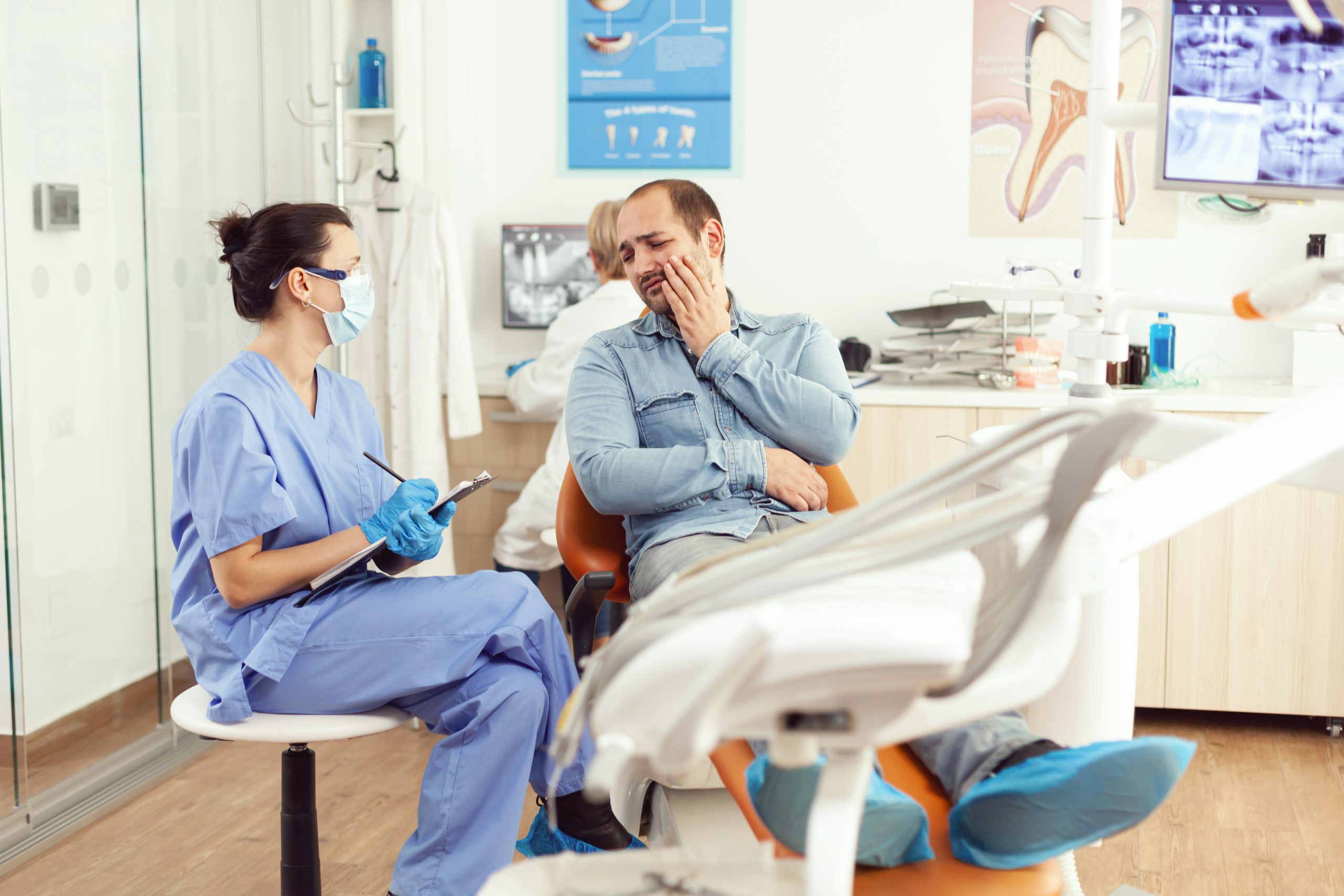 Medical nurse examining patient in paing writing dental problem